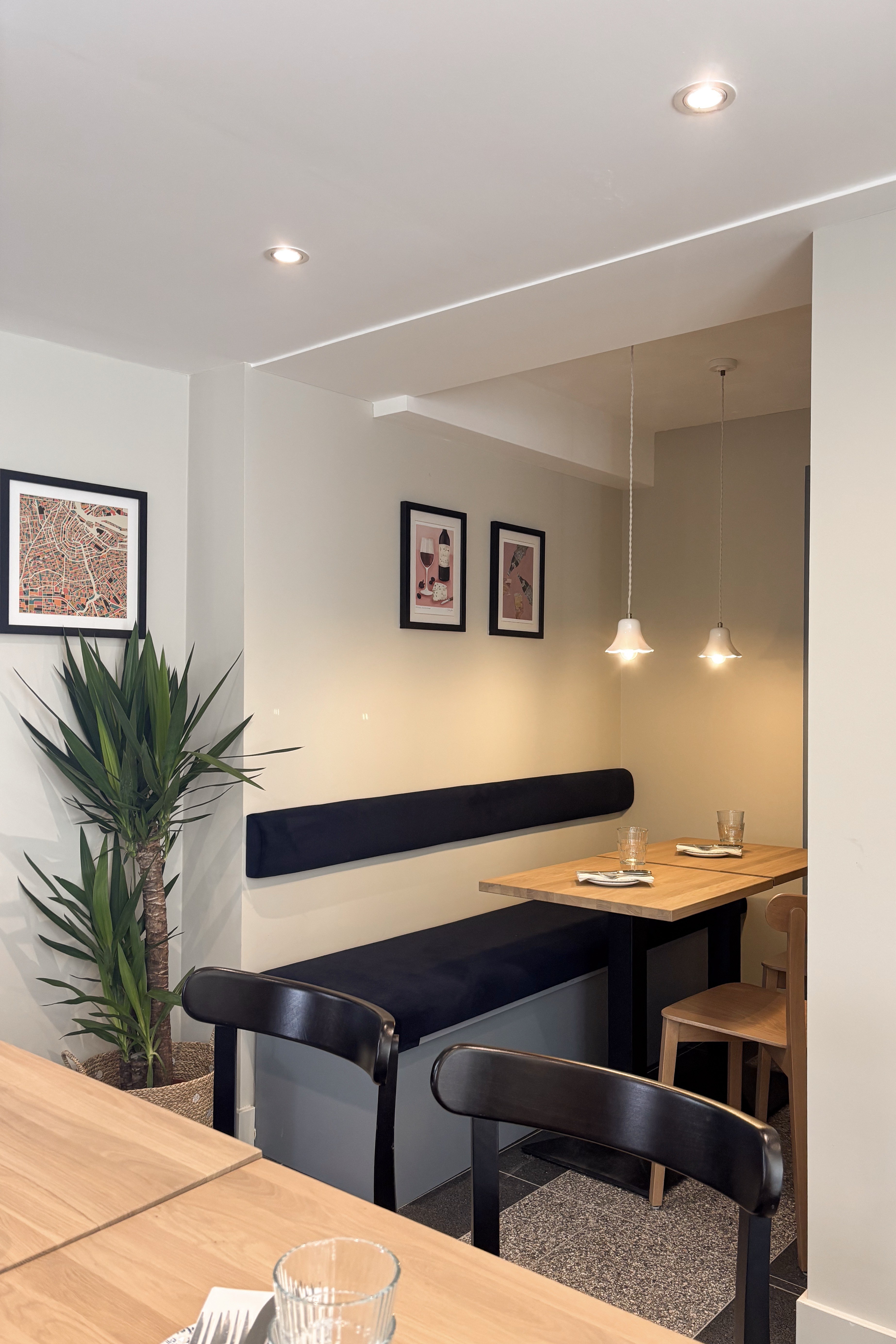 Doorkijk langs compacte eetnissen met donkerblauwe banken, houten tafels en hanglampen.