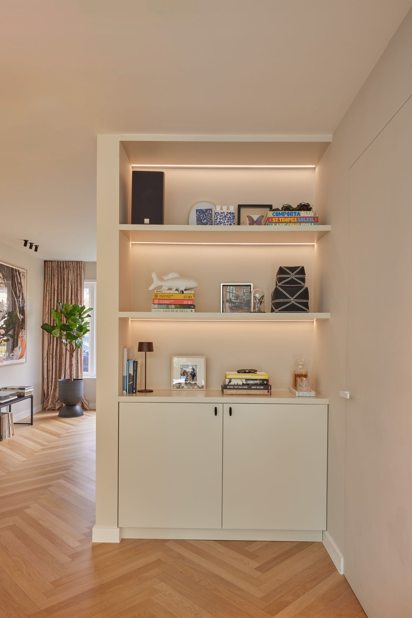 Beige ingebouwde kastnis met verlichte open vakken en rustige styling.