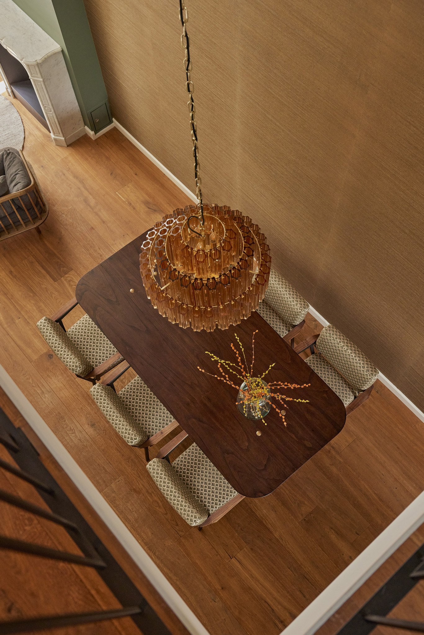 Bovenaanzicht van warme houten eettafel onder een grote rotan kroonluchter.