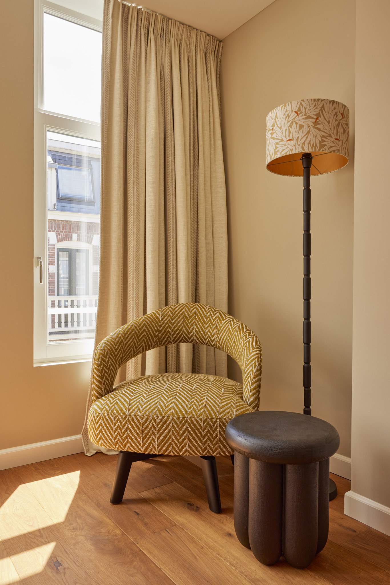 Rustige slaapkamerhoek met olijfgroene fauteuil en zachte beige gordijnen.