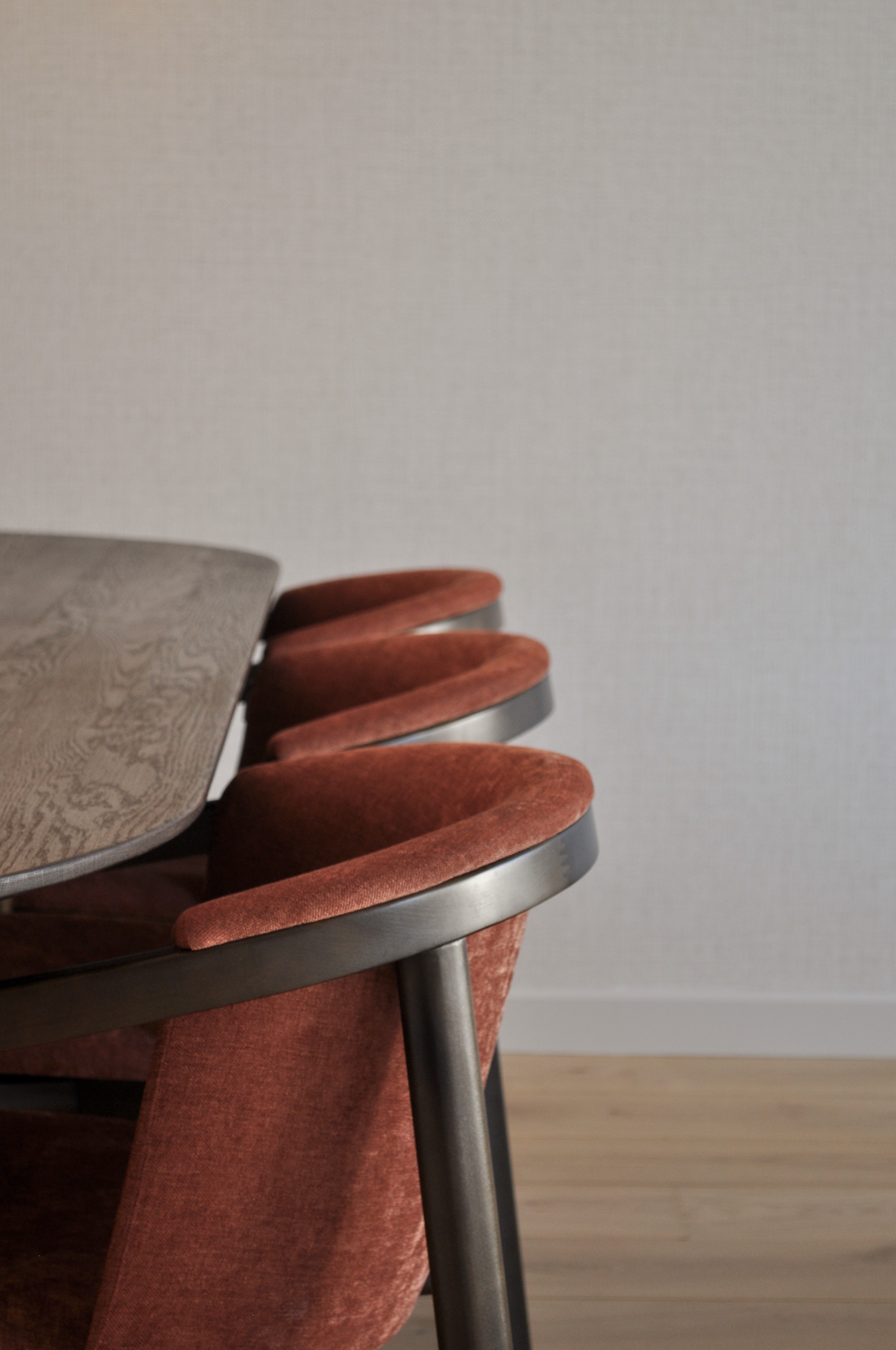 Detail van roestkleurige eetkamerstoelen aan een donkere houten tafel.
