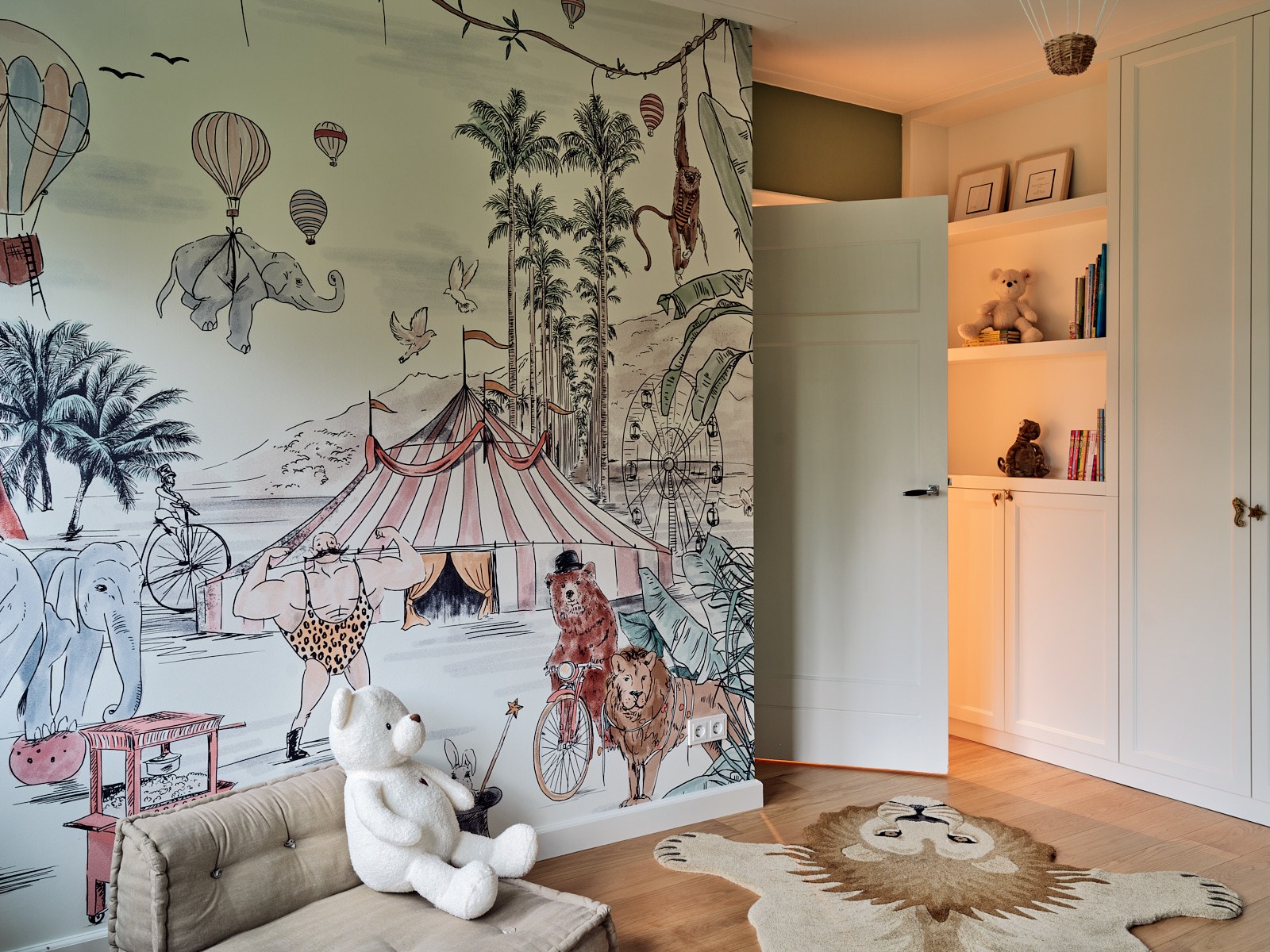 Speelse kinderkamer in Bussum met panoramisch circus- en dierenbehang, witte maatwerkkast, houten vloer en warme ingebouwde verlichting.