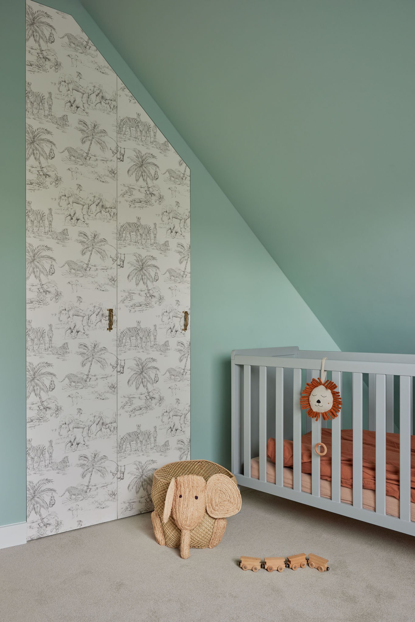 Babykamer met mintgroene wanden, klassiek toilebehang en grijs ledikant.