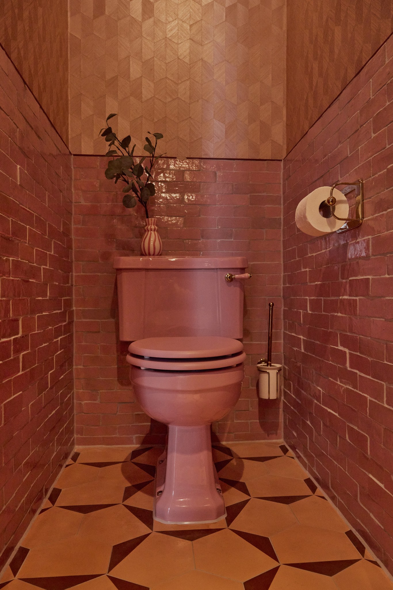 Toiletruimte met roze en terracotta tegels en grafische natuurstenen vloer.