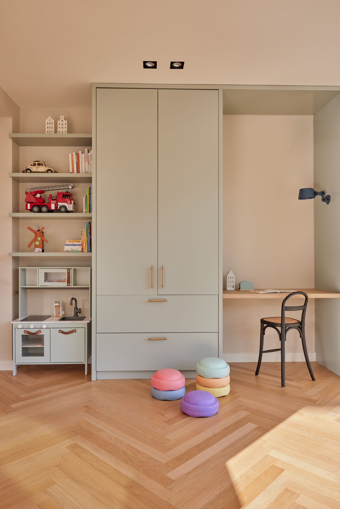 Kinder- en speelruimte met beige ingebouwd bureau, kasten en open opbergnissen.