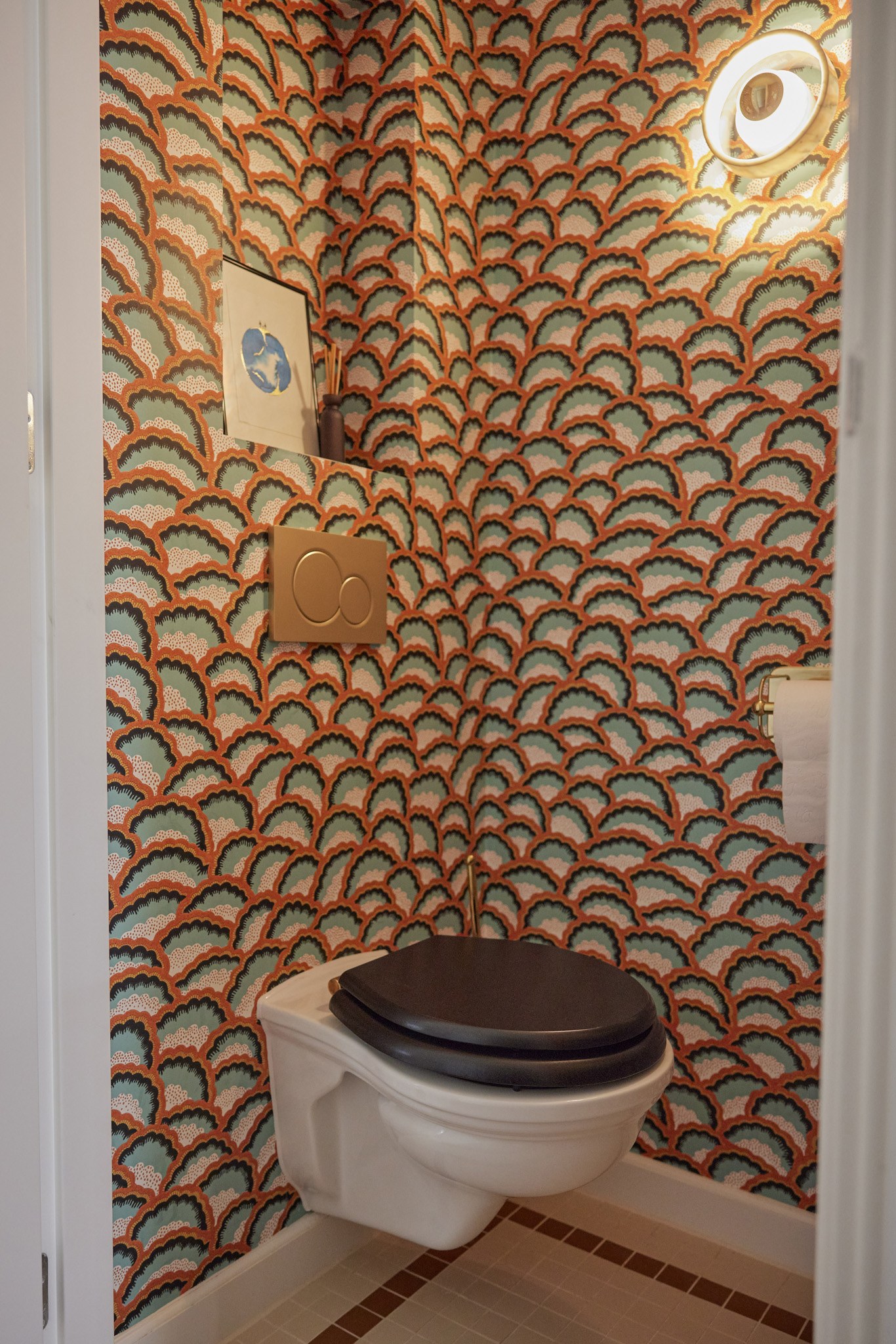 Klein toilet met oranje-groen geschulpt patroonbehang en wandcloset.