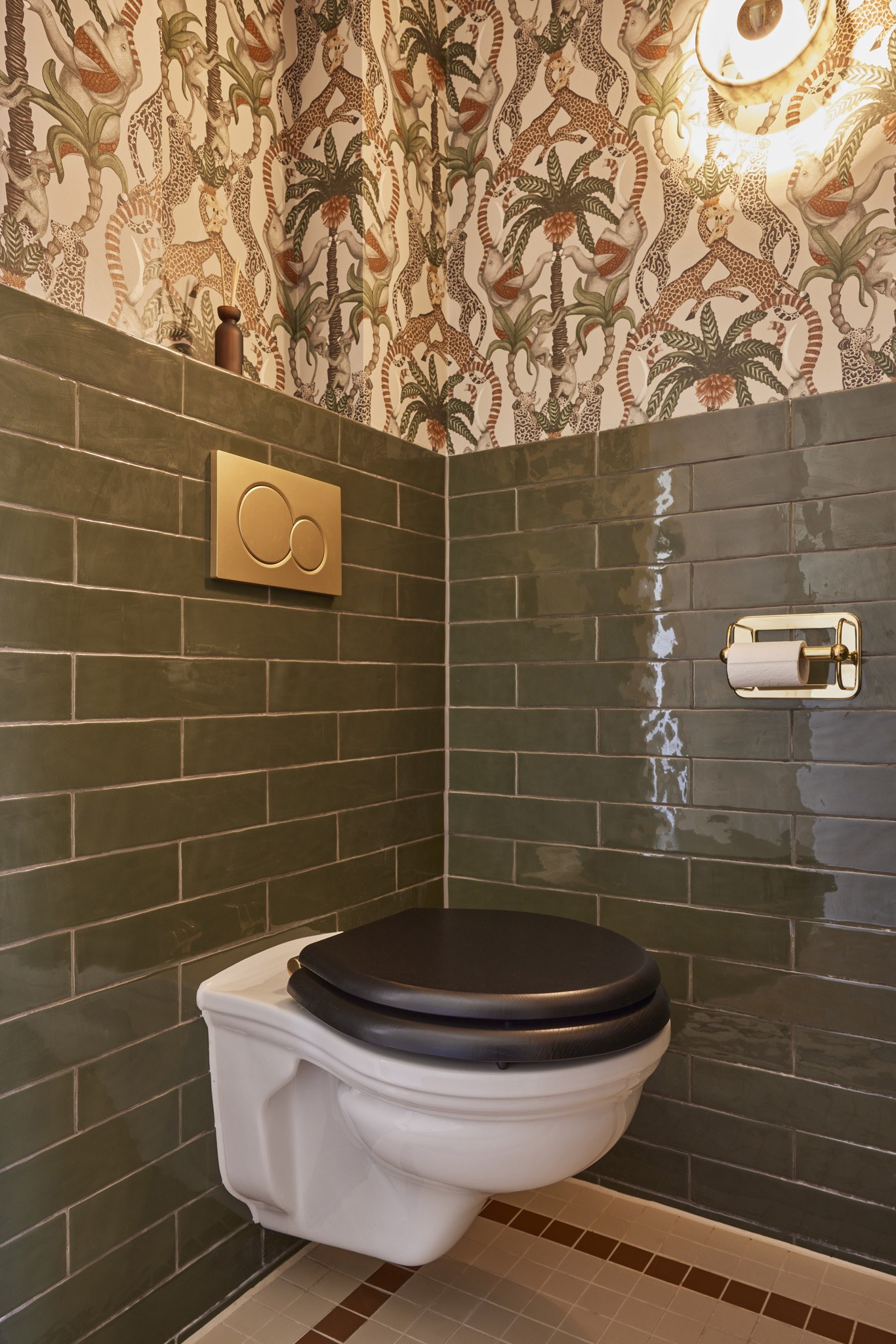 Toilet met groene tegels en botanisch dierenbehang in diepe kleuren.