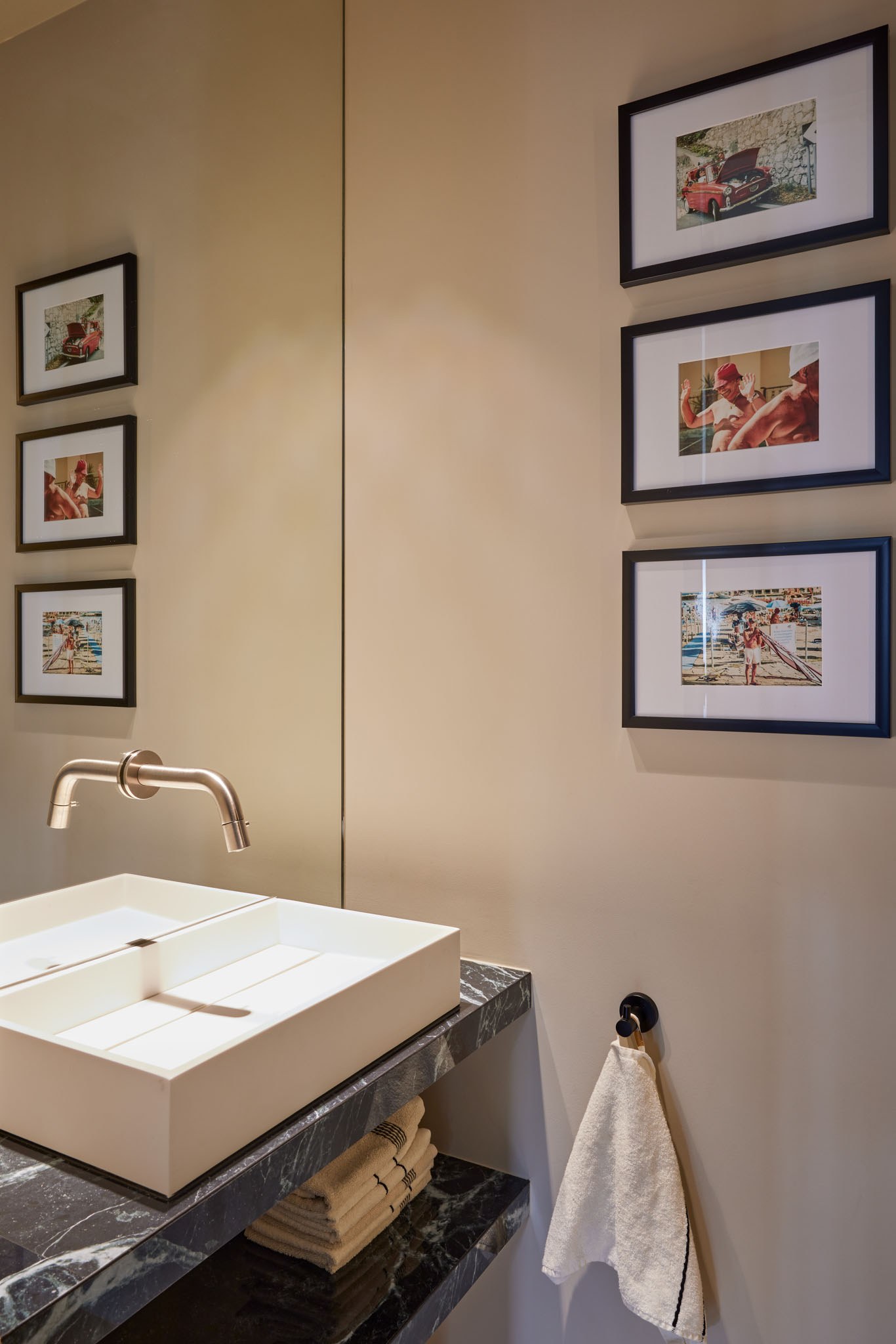 Rustige toiletruimte met natuurstenen en zwart fonteinmeubel, beige wanden en kunst.
